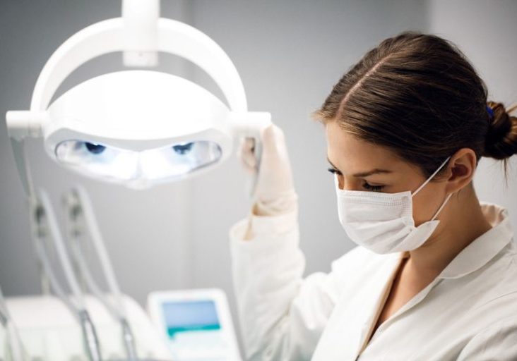 Female dentist looking at patient´s mouth using high density light.